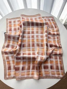 Detailopname van elegante zijden vierkante sjaal met bruin en oranje ruitpatroon