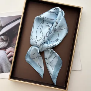 Detail of blue silk scarf with floral print folded in an elegant gift box and magazine