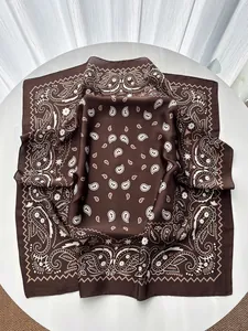 Detail of dark brown silk square scarf with paisley floral pattern on a white table