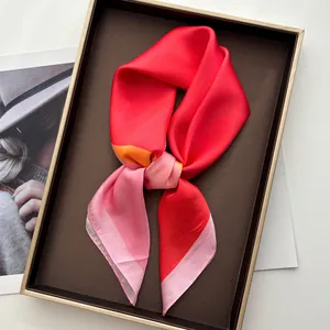 Elegant silk square scarf with vibrant red and pink gradient pattern in a luxury tray