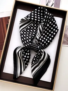 Detailed view of a black and white polka dot silk scarf tied in a gift box