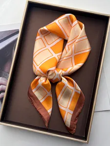 Detail eines orange-weißen Seidenschals, gefaltet in einer braunen Luxus-Ablage