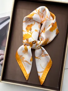 Detail of elegant carnation silk square scarf with yellow floral prints in a tray