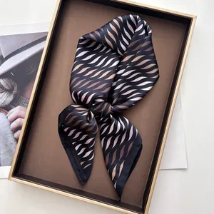 Detalle de elegante pañuelo de seda con estampado ondulado en bandeja dorada