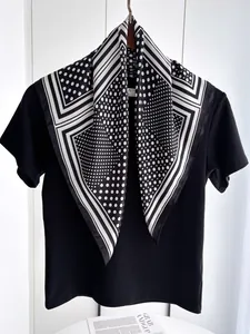 Close-up of black and white silk scarf with polka dots and geometric stripes on a T-shirt