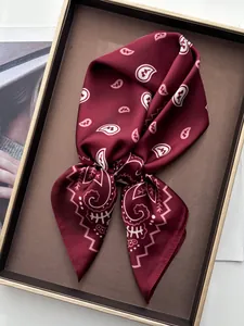 Close-up of knotted burgundy paisley silk scarf showing glossy texture in gift box