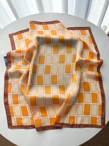 Detail eines orange-beige karierten Kunstseidentuchs mit geometrischem Muster und Satin