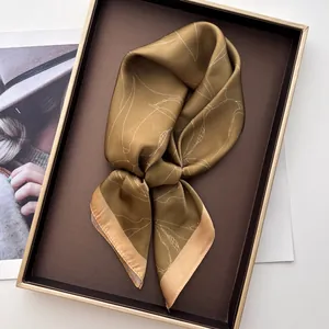 Detail of French retro magnolia print silk scarf folded in a luxury display tray