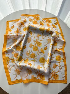 Close-up of elegant carnation pattern on silk-like square scarf with bright yellow edges