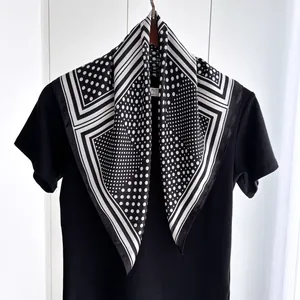 Detailed view of black and white polka dot silk scarf draped over a classic black shirt