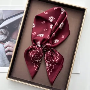 Close-up of burgundy paisley silk scarf neatly folded in a premium gift display box