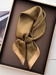 Close-up of olive green floral silk scarf with white plant patterns in a premium gift box