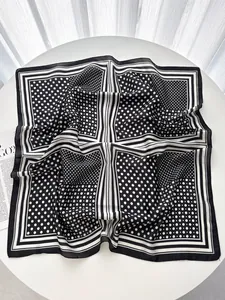 Close-up of silk-like square scarf with black and white polka dot pattern and stripes