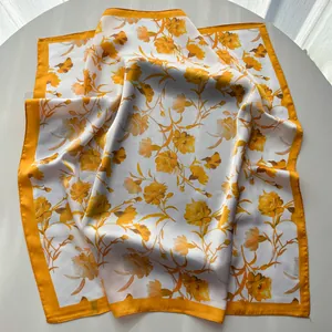 Close-up of elegant carnation silk scarf with vibrant orange floral patterns and glossy texture