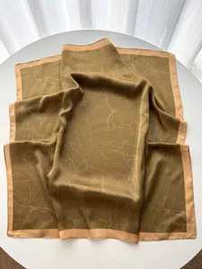 Detail of elegant silk square scarf with white floral print on olive green satin fabric