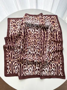 Detailed macro view of leopard print silk scarf with satin texture and dark brown borders
