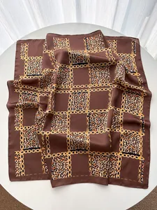 Détail d'un foulard en soie vintage avec motifs de chaînes dorées et imprimé léopard