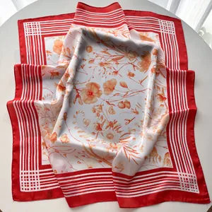 Close-up of floral satin square scarf with red striped border and glossy silk texture