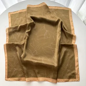 Close-up of olive green silk scarf with white floral print and pink border
