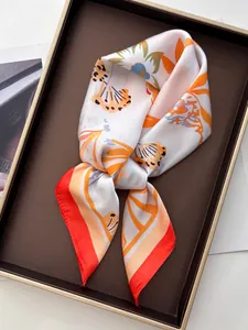 Detail of floral shell print silk scarf with red border on an elegant display tray