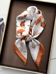 Detailed view of carnation silk scarf with ivory base and vibrant orange floral pattern