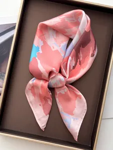 Close-up of pink floral striped silk scarf with smooth satin texture in a luxury gift box