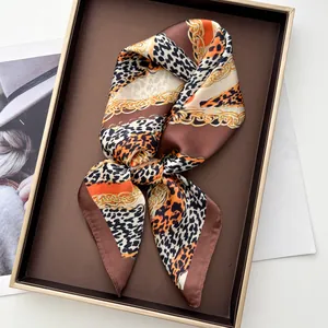 Détail d'un foulard en soie à imprimé léopard et chaîne dans un coffret de luxe