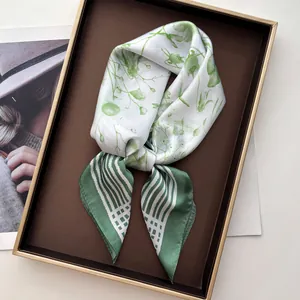 Macro detail of French floral silk scarf with green stripes in a luxury gift box