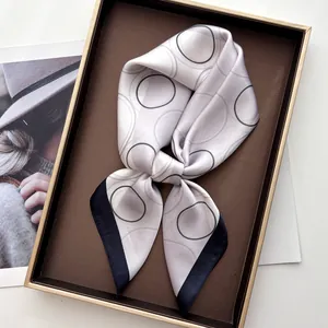 Detail of silk-like square scarf with geometric print inside a luxury gift box