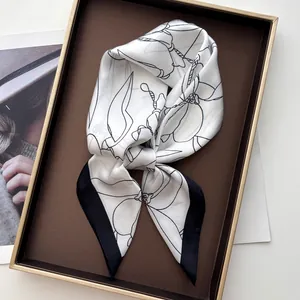 Detail of silk-like scarf with black magnolia floral print and contrasting wide borders