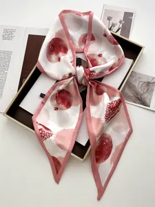 Dettaglio di foulard in seta con stampa di melograno annodato su vassoio dorato