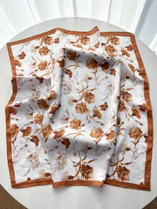 Detail of elegant carnation floral silk scarf with smooth satin finish and rolled edges