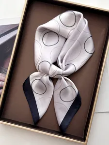 Close-up of geometric print silk scarf with black border on a luxury display tray