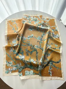 Artistic square silk scarf with floral prints displayed on a table with soft natural lighting