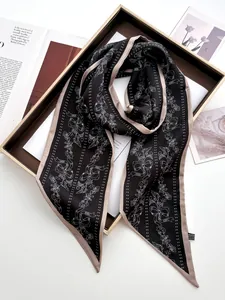 Detailed close-up of floral twilly scarf with bow prints and contrast border on tray