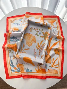 Detail of silk-like scarf featuring beach shell and floral prints on a white table