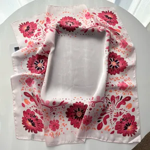 Detailed view of an elegant floral silk-like square scarf with vibrant red patterns