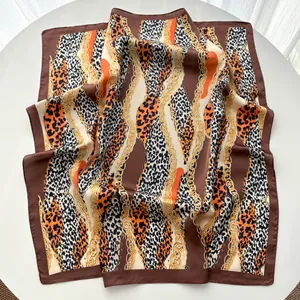 Gros plan du motif léopard et chaîne dorée sur la texture du foulard en satin