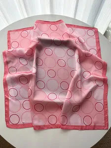 Detail of pink silk scarf with geometric dot patterns on a soft white background
