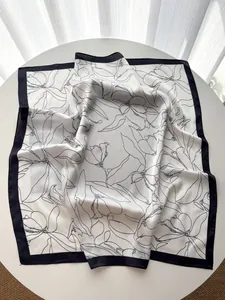 Detail of vintage magnolia print silk scarf with black floral outlines and elegant wide borders