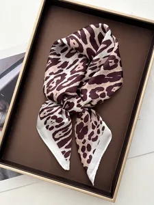 Detailed close-up of leopard print silk scarf with satin finish on a display tray