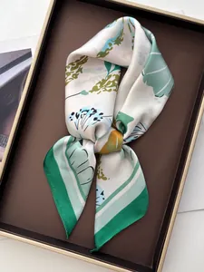 Detail of elegant silk-like square scarf with green floral print tied as a stylish neckerchief
