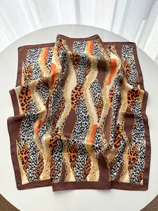 Vue détaillée du foulard en soie rétro avec motif léopard, chaînes dorées et bords orange