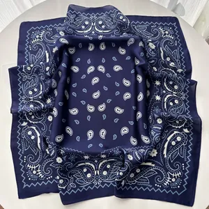 Macro detail of navy blue paisley silk scarf showing the elegant drape and smooth texture