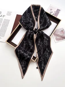 Close-up of elegant black floral silk scarf with bow pattern and gold border detail