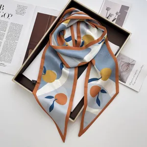 Detailed shot of fruit print satin scarf tied as a twilly on a stylish tray display
