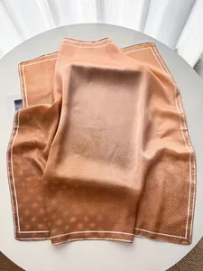Close-up of orange gradient polka dot silk scarf draped on a minimalist table