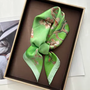 Close-up of green silk scarf with plum blossom print folded in a premium gift box