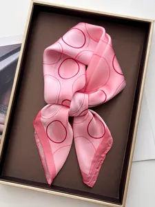 Close-up of pink silk scarf with red geometric circles and elegant burgundy rolled edges