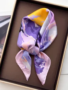 Detailed view of luxury silk-like scarf with abstract floral print on elegant brown tray